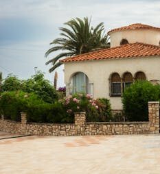 A beautiful Mediterranean-style villa with a garden of vibrant greenery and flowers.