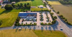 Aerial shot of a solar-powered building and parking lot surrounded by fields in Rehau, Germany.